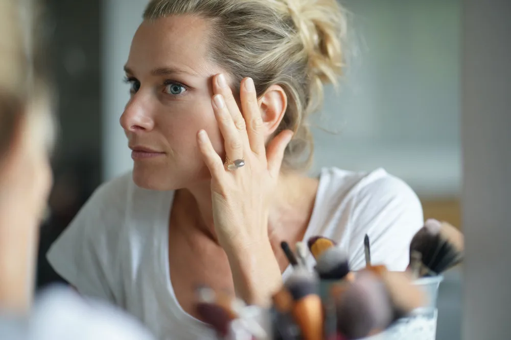 woman looking at her face in the mirror after stopping botox