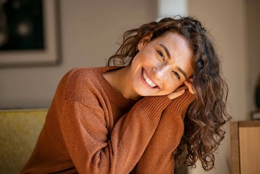A young confident woman smiling in her living room.