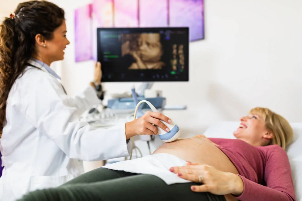 woman at ultrasound appointment looking at her doctor with her baby