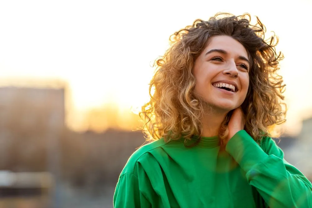 A happy woman smiling in the city during sunset.