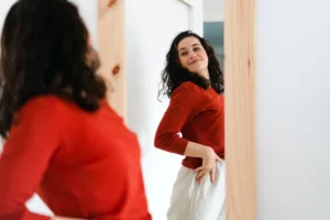 A woman standing in front of the mirror, feeling confident and happy.