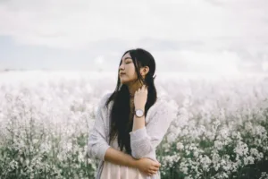 A confident woman standing in a field of flowers.