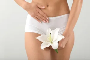 A woman holding a while flower as part of a gynecology concept.