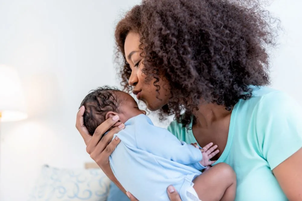 A woman holding her newborn baby after recovering from postpartum.