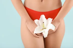 Young woman with flower on color background. Gynecology concept