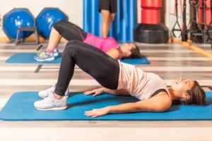 Women doing pelvic exercise with trainer in gym.
