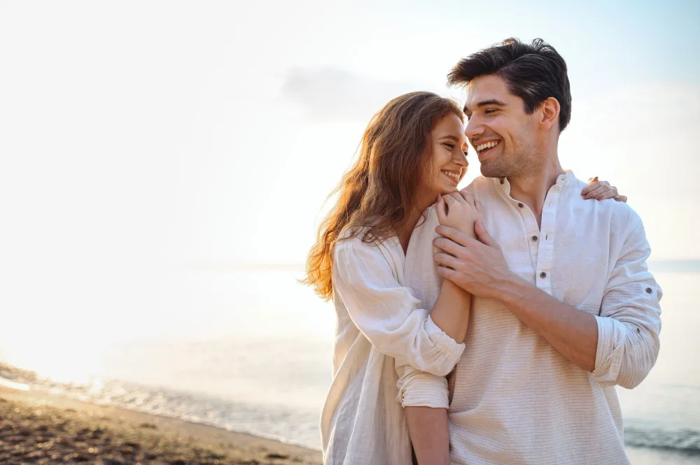 Smiling young couple walking along a beach.